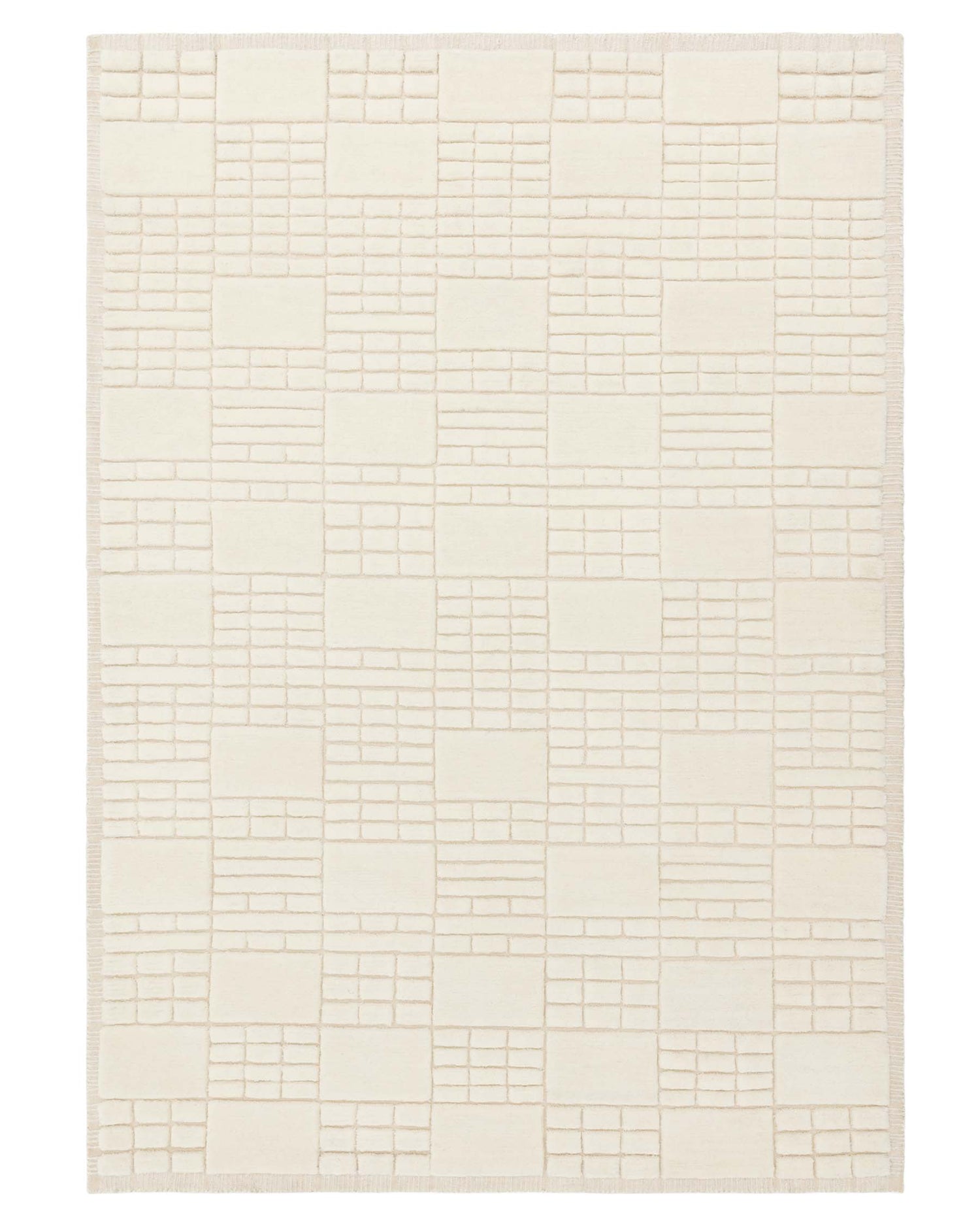 Ivory-coloured area rug with a geometric block pattern and textured details, finished with a fringe edge.
